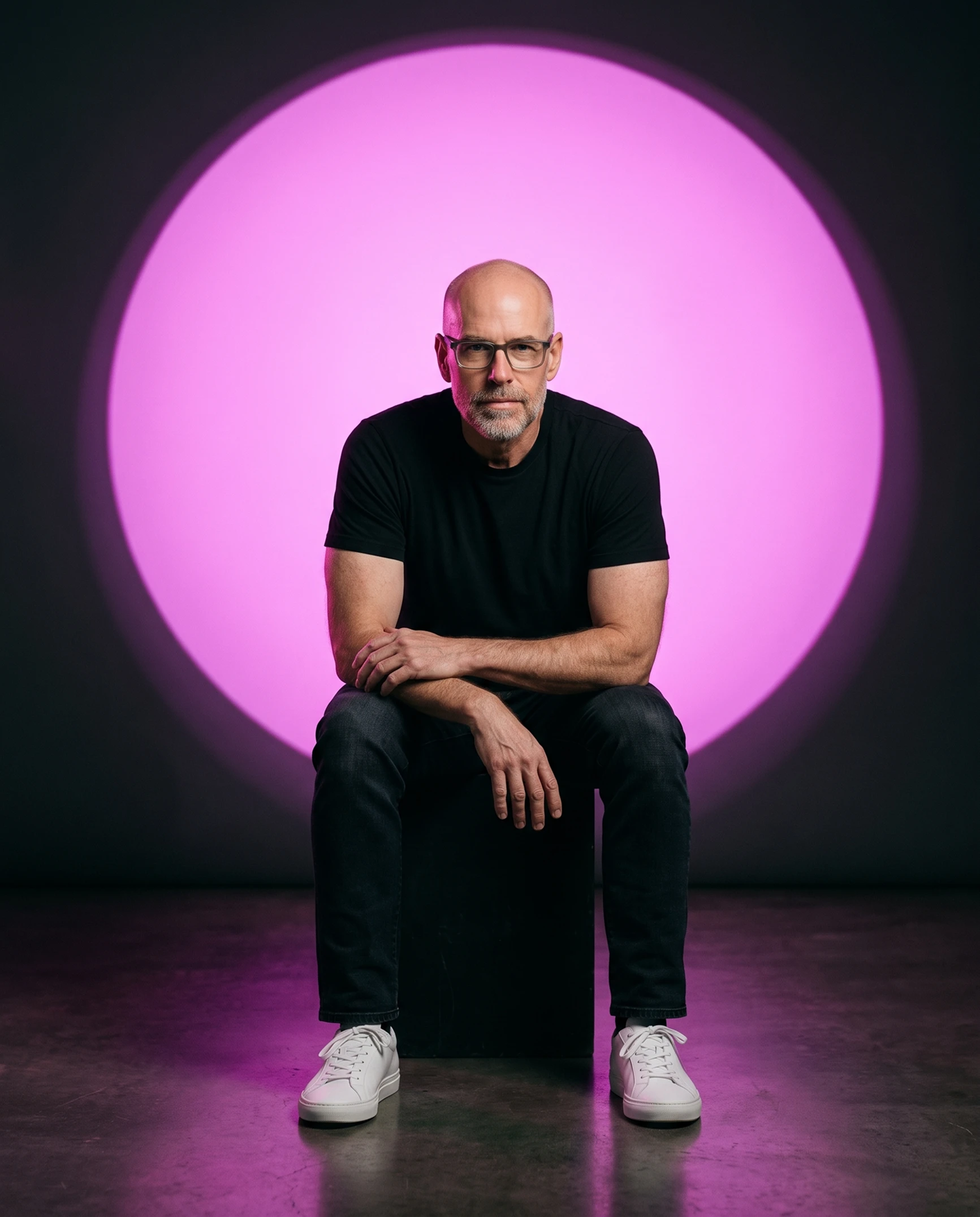 Scott Galloway seated against a magenta circle